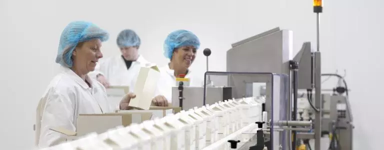 Women putting cartons on a milk manufacturing line