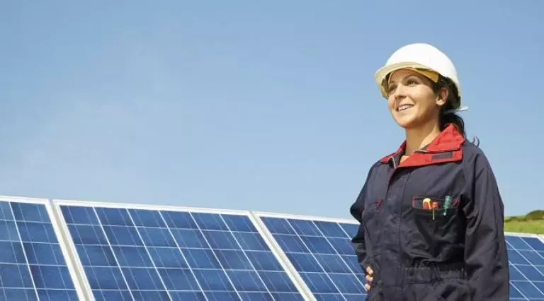 Person wearing a hard hat standing next to solar panels
